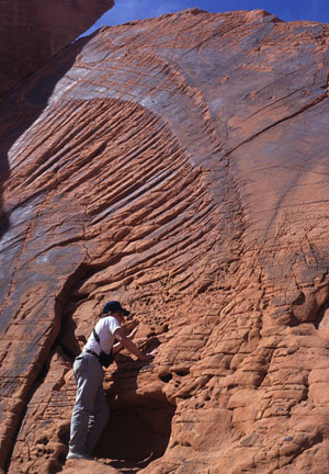 Photo showing joint surface features in sandstone, Valley of Fire State Park, NV. The hackle marks indicate a propagation direction from lower left to upper right. Note that there are two zones of radial breakdown separated by relatively smooth zones. This indicates that the multi-surfaces in the breakdown zones merge into a single smooth one.